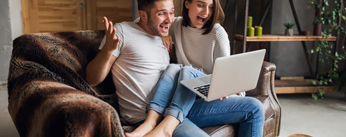 jovem-casal-sorridente-sentado-no-sofá-casa-roupa-casual